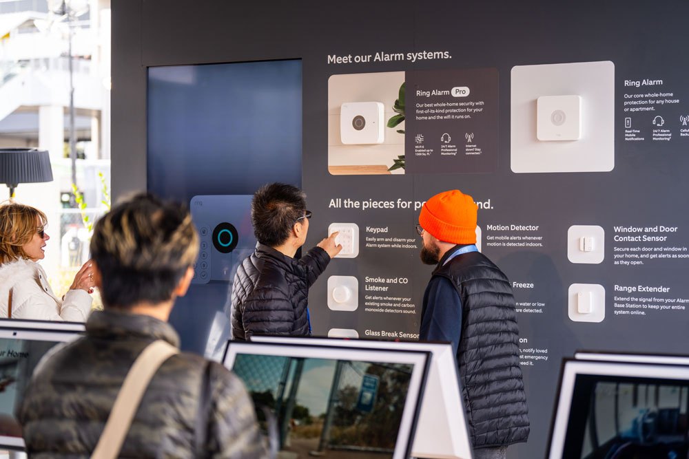 Visitors exploring the alarm-system wall inside a demo home