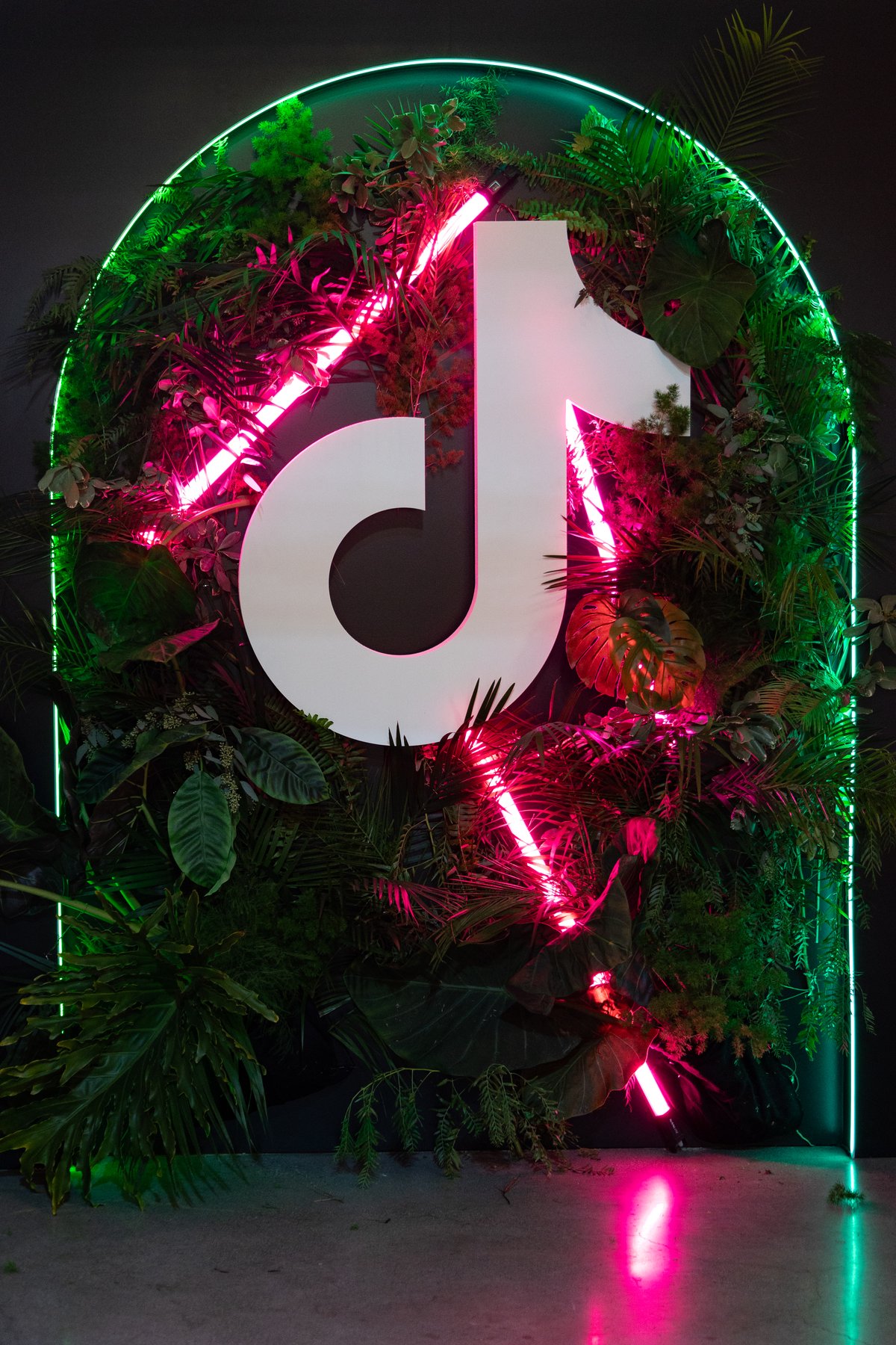 The TikTok mark in neon and greenery